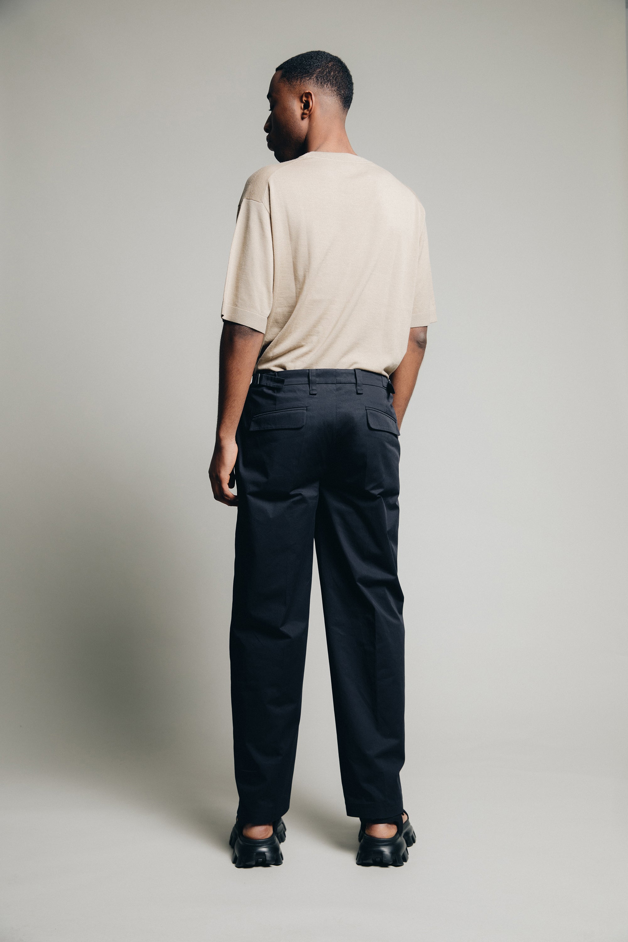 1c1y ss23 m1kyta II straight black suit with pleats organic cotton back shot showing signature pockets sand coloured tucked in shirt and wide cut