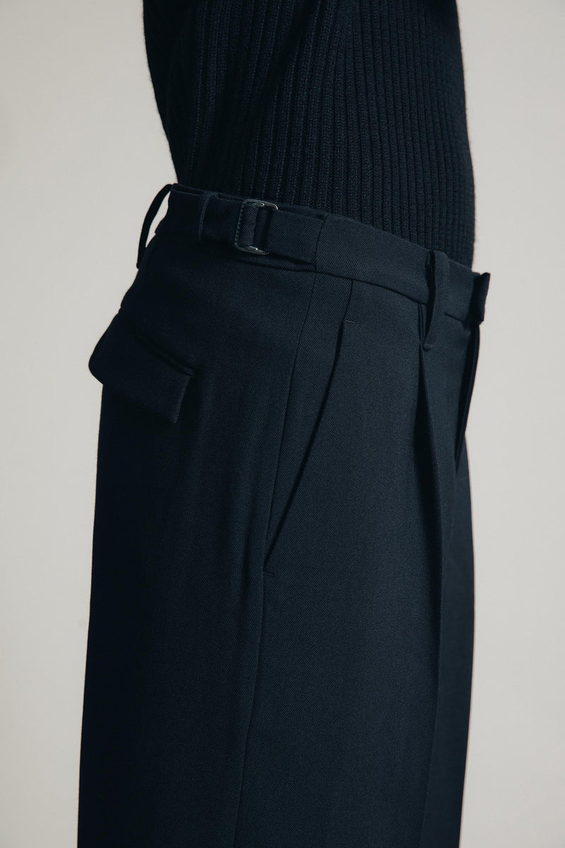 detail shot of m1kyta 1c1y wide trousers in studio with side adjusters buckles on the side showing the pleats back pocket and wool texture 