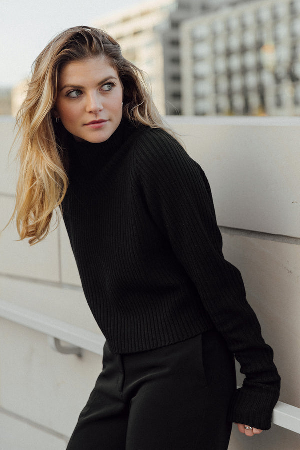 Model in merino knit yul1a 1c1y leaning against wall and looking backwards