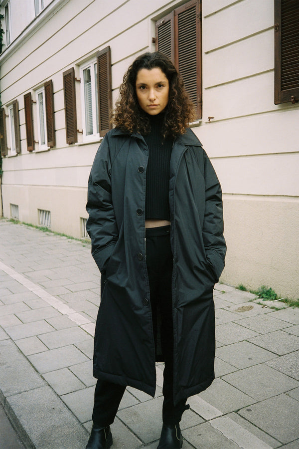 Marie Model standing on pavement wearing recycled nylon One Raincoat 1C1Y with cropped Merino Knit beneath
